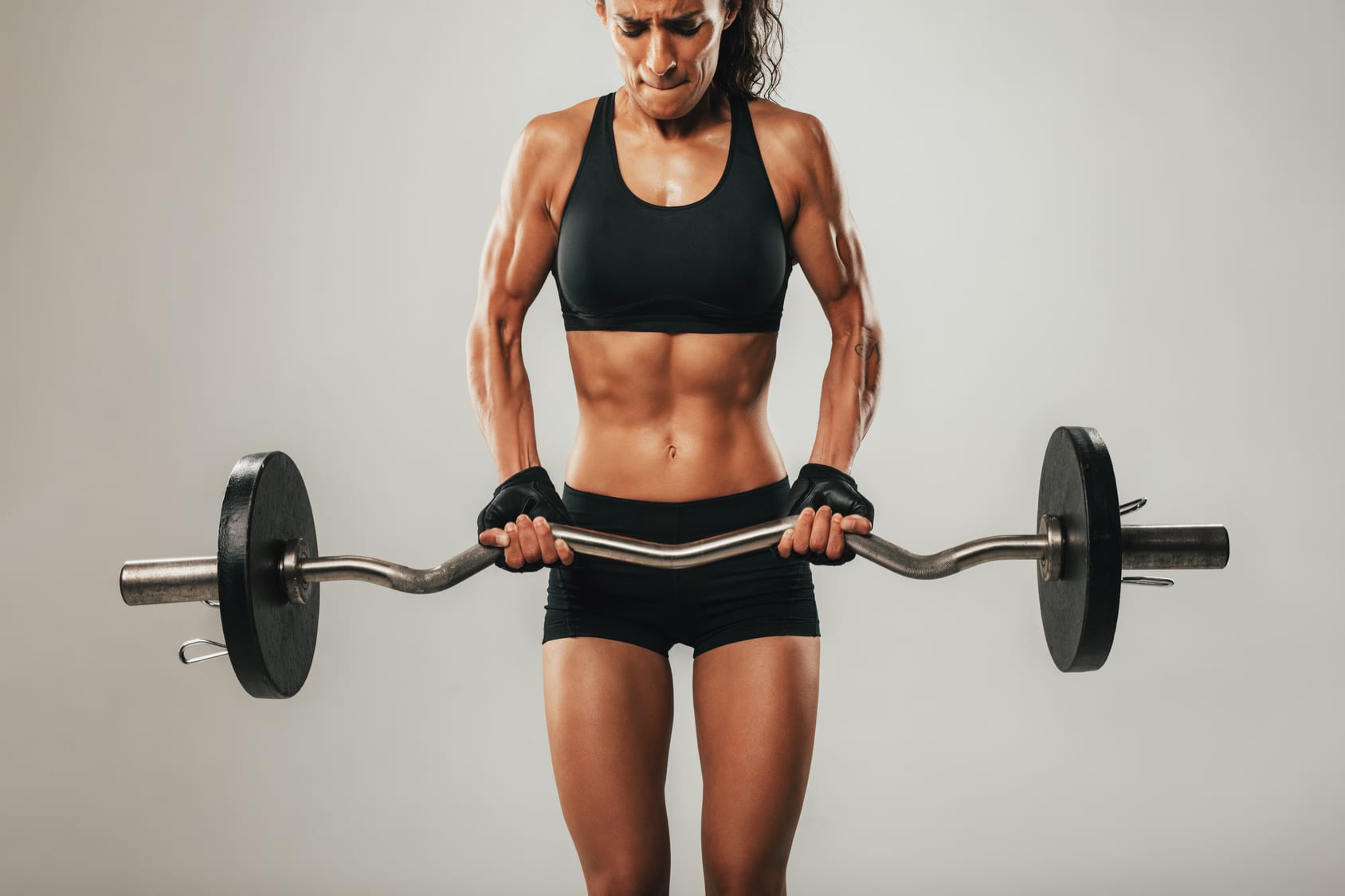 woman lifts a heavy barbell in gym